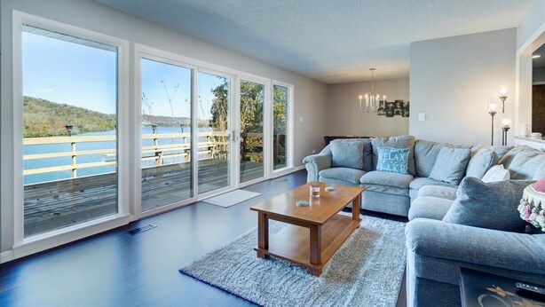 A spacious living room with a large sliding glass door leading to a deck overlooking a body of water. - Breathtaking Lake View w/Pool Nearby!- Knoxville/Oak Ridge (Knoxville)