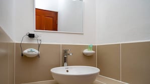 A bathroom with a white sink, a mirror, and a wooden door in the background. - The Orchid Studio Experience" (Caye Caulker)