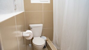 A small, clean bathroom with a toilet, a bidet, and a shower curtain. - The Orchid Studio Experience" (Caye Caulker)