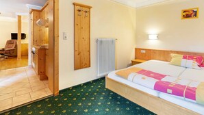 Une chambre d’hôtel avec un lit, une armoire en bois, un radiateur et une chaise.