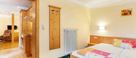 A hotel room with a bed, a wooden wardrobe, a radiator, and a chair.