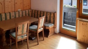 A wooden dining table with chairs, a bench, and a window with a view of a fence. - Spacious Apartment in Salzburg near Ski Area (Saalbach-Hinterglemm)
