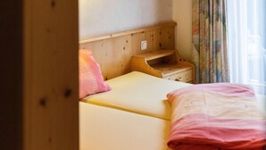 A bedroom with a wooden headboard, a bedside table, and a window with curtains. - Spacious Apartment in Salzburg near Ski Area (Saalbach-Hinterglemm)