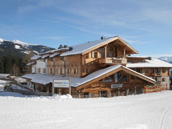 Un chalet en bois doté d’un balcon, entouré de montagnes enneigées.