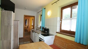 A compact kitchen with a dining area, a microwave, a sink, and a window with curtains. - Pleasant Apartment in Langenfeld With Sauna (Laengenfeld)
