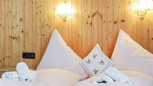 A wooden-paneled room with two beds, each with white linens and pillows. There are two wall-mounted lights on either side of the beds. - Sunlit Apartment near Ski Area in Längenfeld (Laengenfeld)