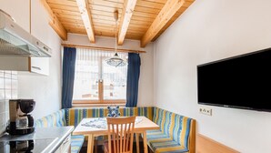 A cozy kitchenette with a built-in stove, a coffee maker, and a window with curtains. - Sunlit Apartment near Ski Area in Längenfeld (Laengenfeld)