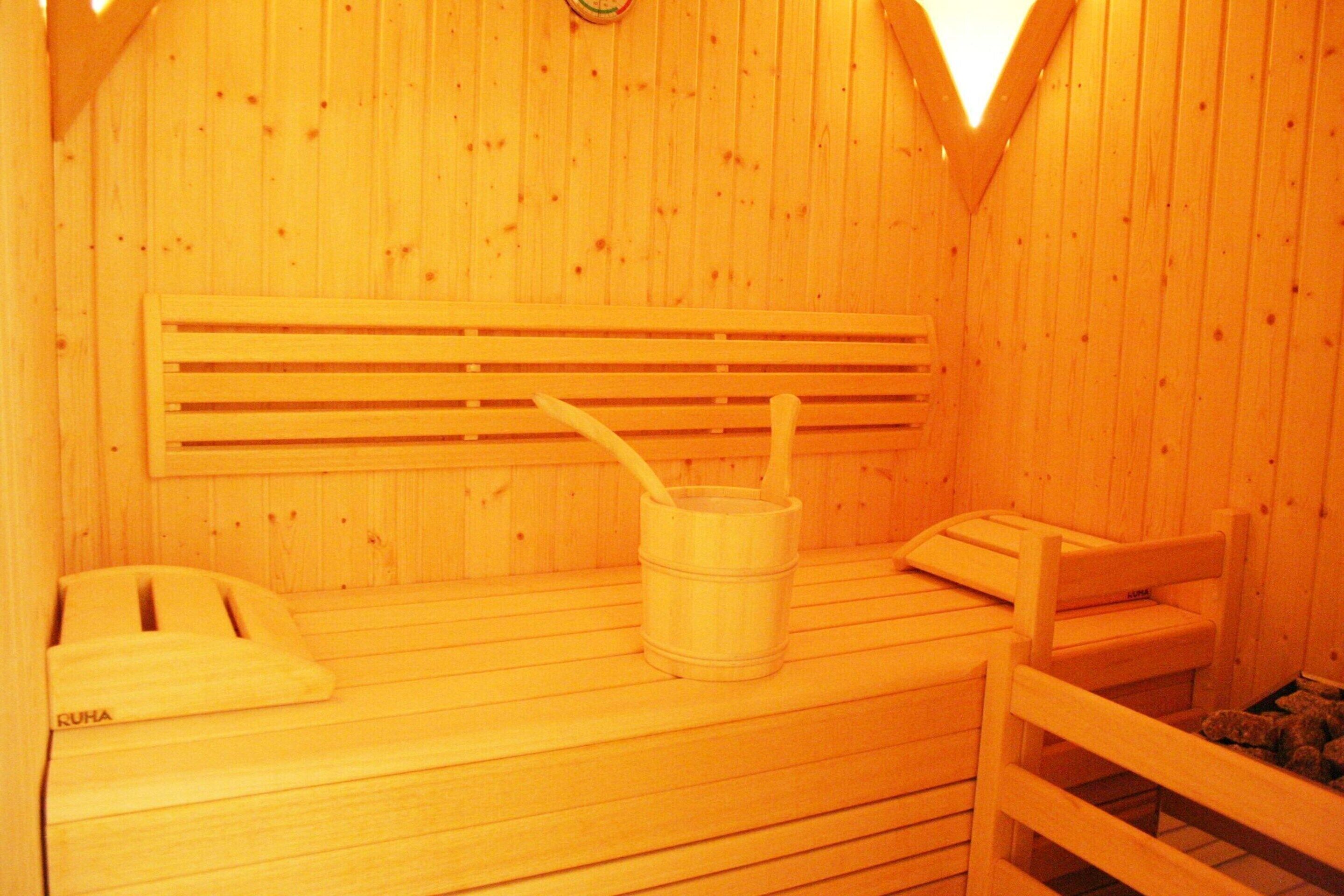 A wooden sauna with benches and a wooden bucket.