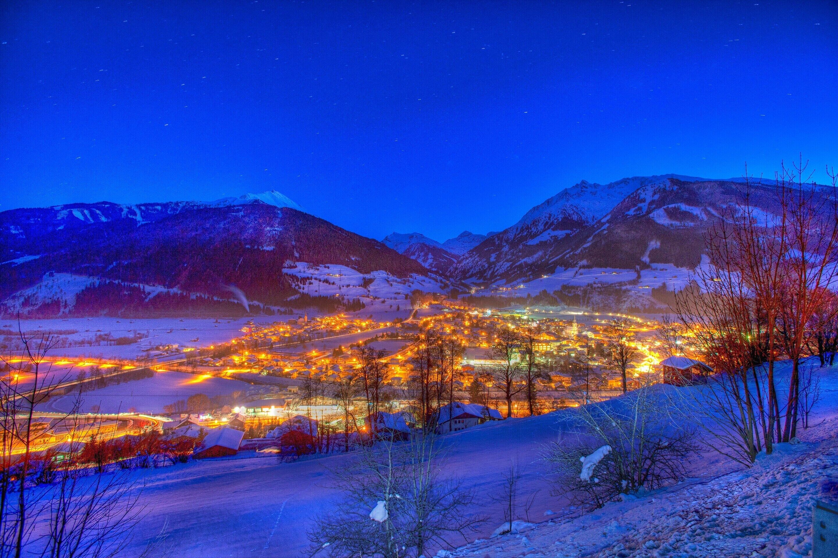 A town at night with snow-covered mountains in the background.