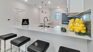 A modern kitchen with a white countertop, stainless steel sink, and bar stools. - 2 Bedrooms / 2 Bathrooms / Storey Lake (3120-403 PC) (Kissimmee)