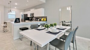 A modern kitchen with white cabinets, a central island, and a dining area with a white table set for four. - 2 Bedrooms / 2 Bathrooms / Storey Lake (3120-403 PC) (Kissimmee)