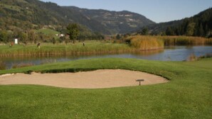 A golf course with a sand bunker, a pond, and a mountain backdrop. - Chalet in Stadl an der Mur / Styria Near ski Area (Stadl-Predlitz)