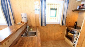 A compact kitchen with wooden walls, a stainless steel sink, a coffee maker, and a built-in oven. - Chalet in Stadl an der Mur / Styria Near ski Area (Stadl-Predlitz)