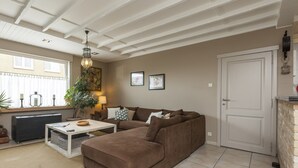 A living room with a brown sofa, a white coffee table, a lamp, and a plant. - Vintage Villa in Knokke-Heist near Beach (Knokke-Heist)