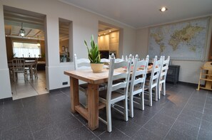 A dining area with a wooden table and white chairs, a potted plant, and a world map on the wall. - Vintage Villa in Knokke-Heist near Beach (Knokke-Heist)