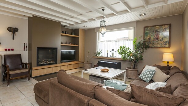 A living room with a TV, sofa, and a dining table. - Vintage Villa in Knokke-Heist near Beach (Knokke-Heist)