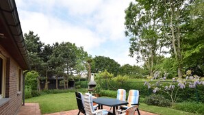 A patio with a brick floor, a table, and two chairs. - Family Home Close to the Beach (Bredene)