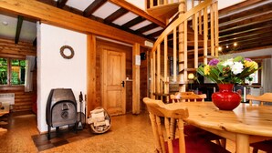 Un intérieur en bois avec un escalier en colimaçon, une table à manger avec des chaises et une cheminée.
