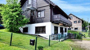 Une cabane en rondins dotée d’un balcon, d’un petit porche et d’une cour clôturée.