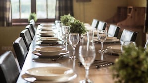 Une longue table à manger, dressée avec des assiettes, des verres et une petite plante en pot.