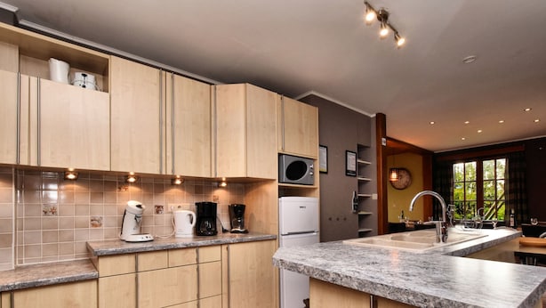 Une cuisine moderne avec des meubles en bois, un four à micro-ondes encastré et un plan de travail en granit.