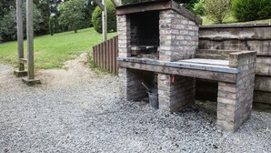 Une cuisine extérieure en briques avec une cheminée, une pergola en bois et un chemin de gravier.