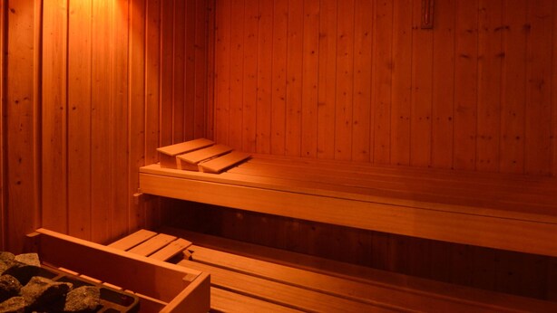 Een sauna met houten banken en een heater aan de muur.