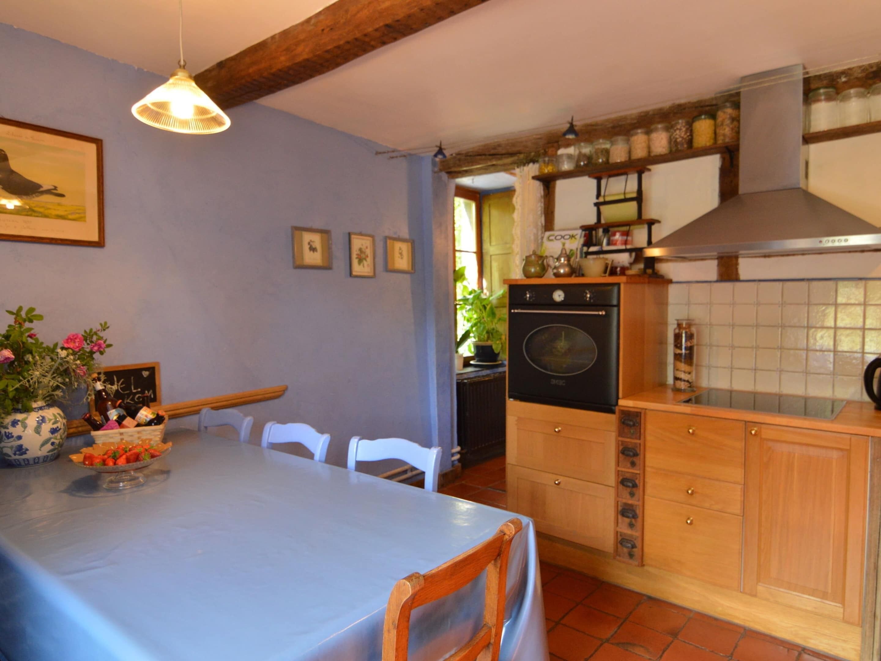 Een keuken met een eettafel, stoelen, een fornuis en kastjes.