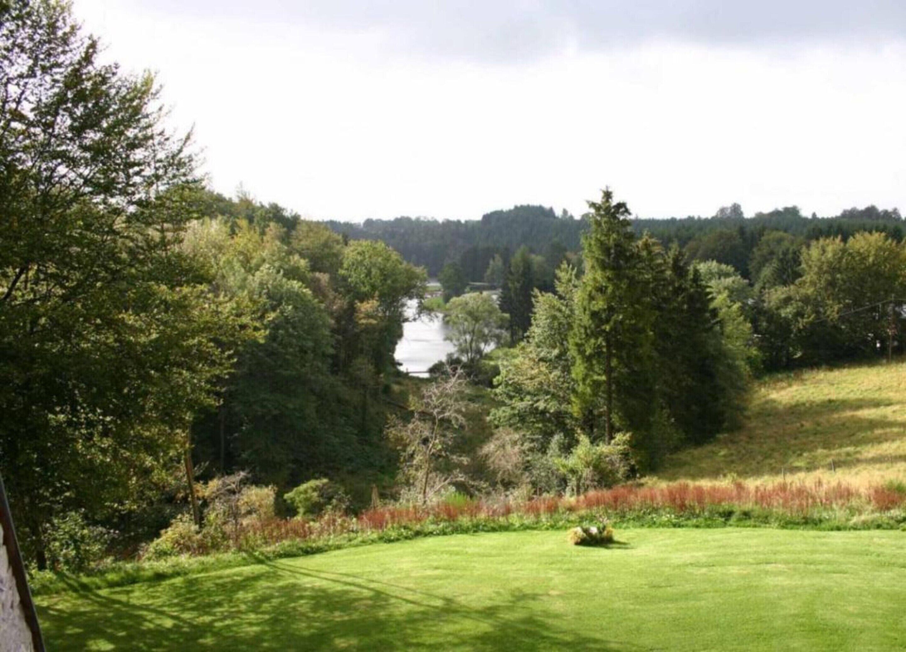 Un campo da golf con un lago sullo sfondo, circondato da una fitta foresta.