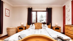 Una camera da letto con un letto in legno, due comodini con lampade, un cesto in vimini e una finestra con tende.