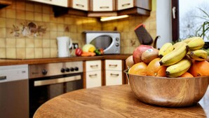Una cucina con una ciotola di frutta su un tavolo di legno, un forno a microonde e dei mobili.
