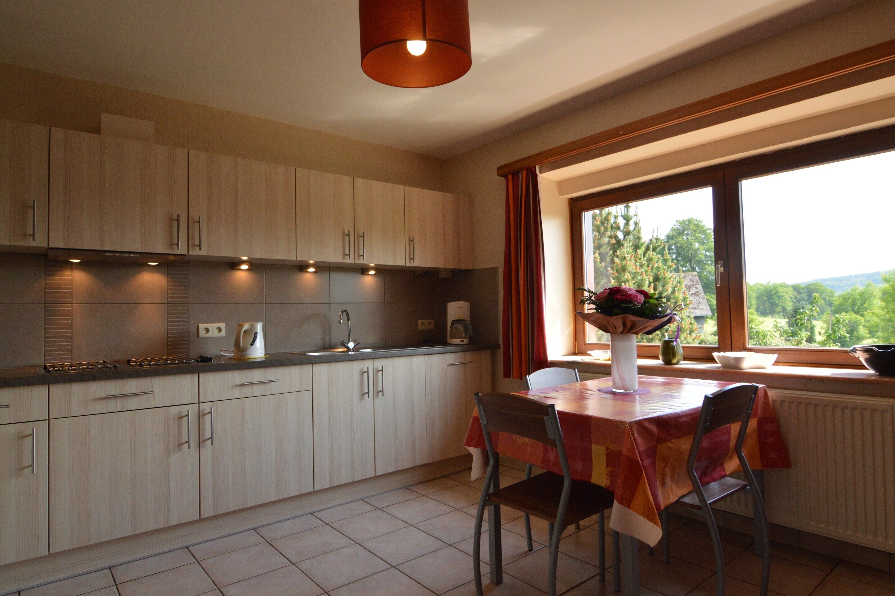 A kitchen with a dining area, a window with a view, and a table with chairs.