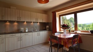 A kitchen with a dining area, a window with a view, and a table with chairs. - Ondenval Stay With Sauna (Waimes)
