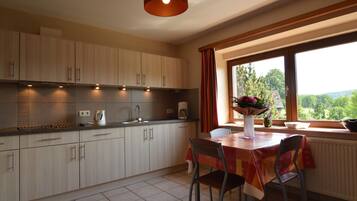 A kitchen with a dining area, a window with a view, and a table with chairs.