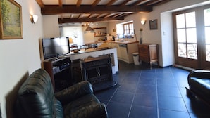 A cozy living room with a fireplace, a television, and a sofa. - Cozy Cottage Near River (Vresse-sur-Semois)