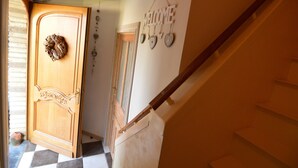 Eine Holztür mit einem dekorativen Kranz, einem 'WELCOME'-Schild mit herzförmigen Verzierungen und einer Treppe mit einem Holnänder.