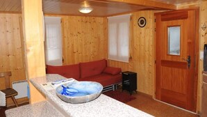 Interior de madera con un sofá rojo, una mesita con un cuenco y una puerta con ventanal.