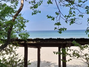 Blick auf einen Strand mit einer Holzkonstruktion und Bäumen im Vordergrund.