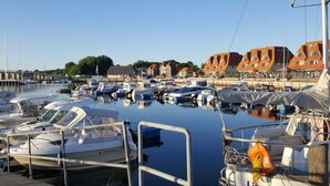 A marina with multiple boats docked, a clear sky, and buildings with orange roofs in the background. - Modernes Ferienhaus mit Sauna in Wiek am Meer (Wiek)