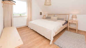 A bedroom with a large bed, wooden floor, a hanging light fixture, a window with curtains, and a view of the outdoors. - Spacious Apartment in Leopoldshöhe near Teutoburg Forest (Leopoldshoehe)