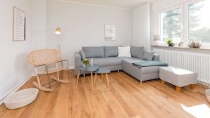 A modern living room with a grey sectional sofa, a small round table, and a rocking chair. - Spacious Apartment in Leopoldshöhe near Teutoburg Forest (Leopoldshoehe)