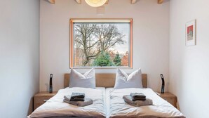 A double bed with a view of trees through a window.