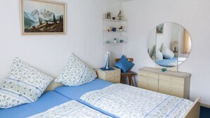 Une chambre à coucher comprenant un lit, une commode, des étagères, un miroir et un tableau.