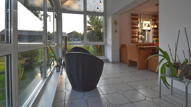 A modern interior with large windows, a wicker chair, and a dining area with a bar. - Fantastic Holiday Home in Schonsee, Bavaria (Schoensee)