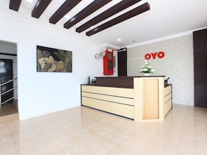 Uma receção com design moderno, uma placa afixada na parede com a inscrição "OYO" e uma grande obra de arte emoldurada.