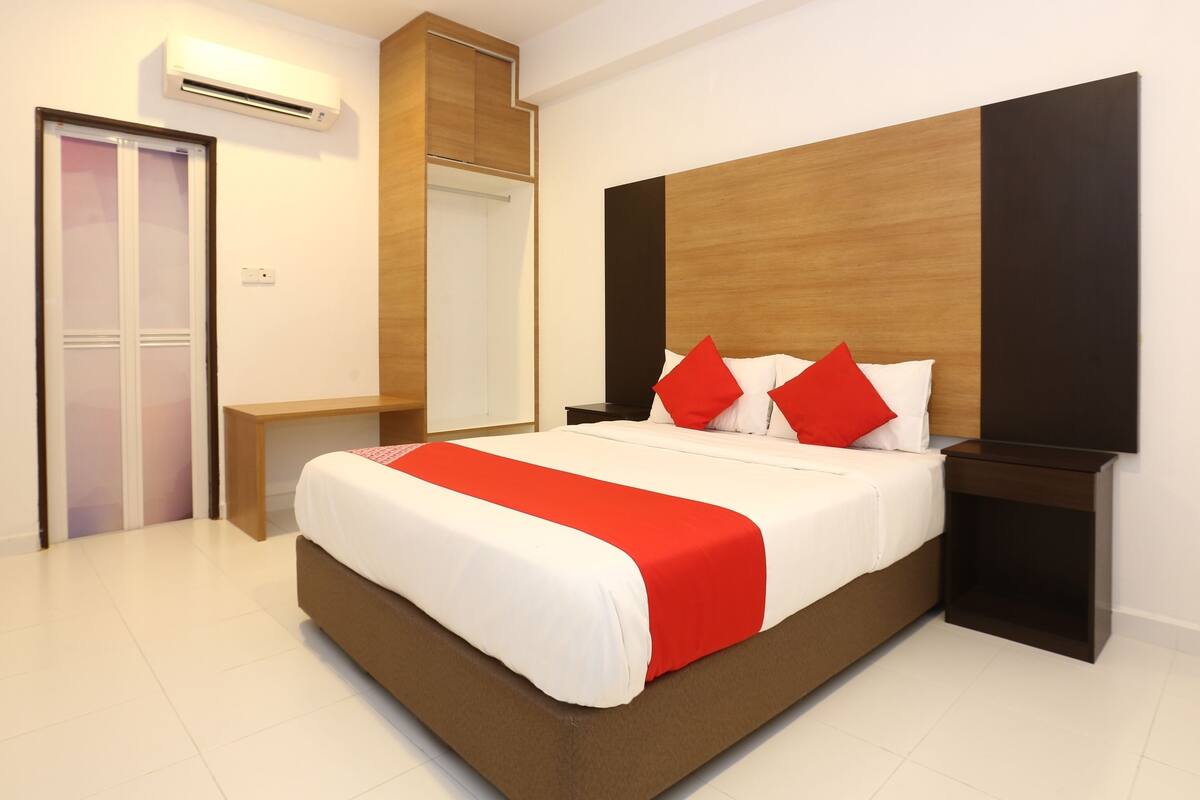 A modern bedroom with a large bed, a wooden headboard, a bedside table, and a wardrobe.