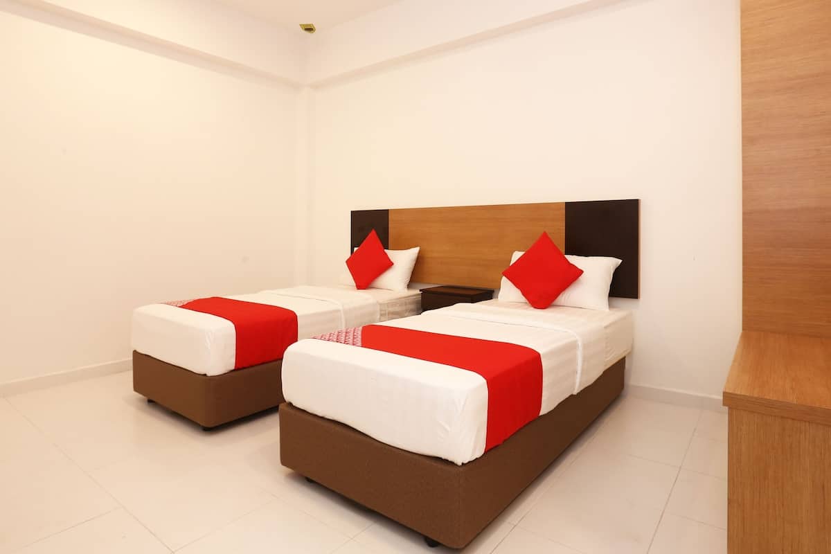 A hotel room with two beds, each with a wooden headboard, white bedding, and red accents.