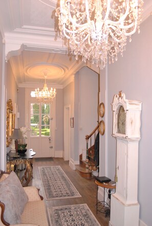 A hallway with a chandelier, a grandfather clock, and a door leading outside. - Beautiful Manor house with heated pool in a village,  close to sandy beaches. (EPARGNES)