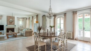 A spacious living room with a dining area, a fireplace, and a large window with curtains. - Beachside Bliss in Gassin (Gassin)