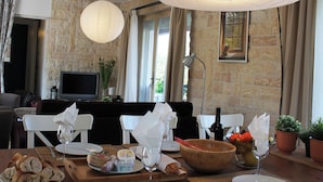 A dining area with a stone wall, a television, and a view of the outdoors. - Villa in Languedoc With Pool Near Historic Cities (Rousson)